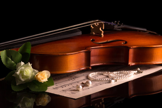 Violin and Notepad with notes, jewelry and flowers isolated on black
