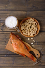 Beer mug and fish with peanuts on wooden table