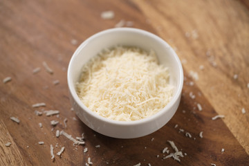 grated aged italian parmesan cheese in white bowl on table