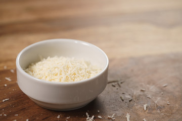 grated aged italian parmesan cheese in white bowl on table