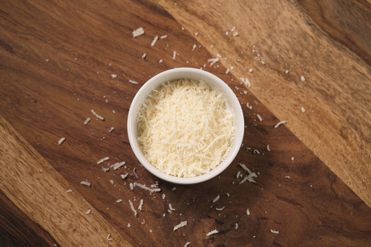 Grated Aged Italian Parmesan Cheese In White Bowl On Table