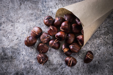 Obraz premium Roasted chestnuts on an old board. healthy food concept