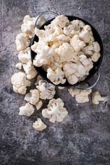Fresh organic cauliflower cut into small pieces in ceramic bowl on gray background