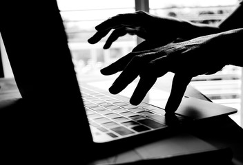 Cyber crime hand reaching out through laptop computer and attack signifying in internet theft while...