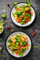 Fresh salmon salad with avocado, orange and green vegetables.