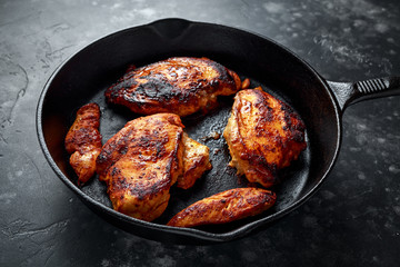 Cooked chicken fillets, breast supremes in rustic cast iron skillet.