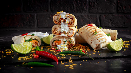 Healthy grilled chicken and parsley wraps, loaded with cheese, served with greek yogurt deep, chillies and lime slices - obrazy, fototapety, plakaty