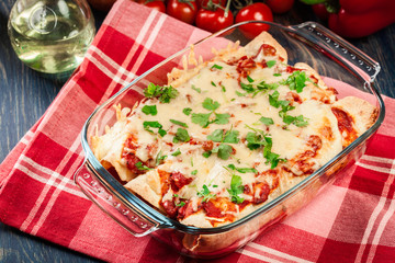 Traditional mexican enchiladas with chicken meat, spicy tomato sauce and cheese in heat resistant dish