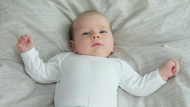 Beautiful baby on back on bed, top view