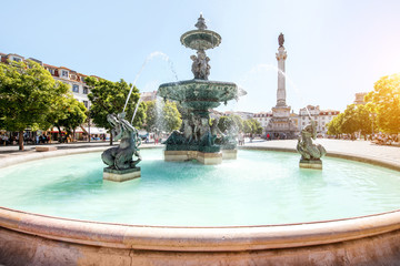 Beautiful view on the fountain on the Rossio square with column during the sunny day in Lisbon city, Portugal