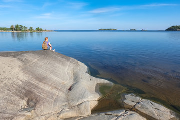 Landscape on a big lake and a girl sitting on a stone shore