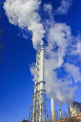White smoke goes from a pipe on a background of blue cloudless sky