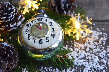 Naklejka na ściany i meble Christmas decoration with retro alarm clock christmas toy,pine cones and garland lights on old wooden background.Merry Christmas,Happy New Year.Winter holidays concept.Copy space.Selective focus.