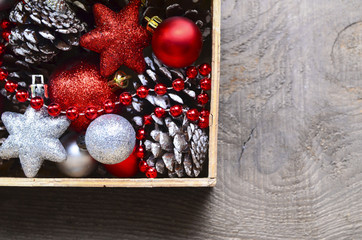 Christmas tree decoration: red and silver shiny balls,stars and pine cones in a vintage wooden box.Prepare for Christmas Eve or New Year winter holidays.Selective focus.
