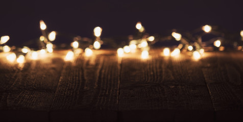 Blurred christmas lights on wooden rustic table. Moody christmas background with copyspace