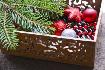 Fototapeta na wymiar Christmas tree decoration: red and silver shiny balls,stars and pine cones in a vintage wooden box.Prepare for Christmas Eve or New Year winter holidays.Selective focus.