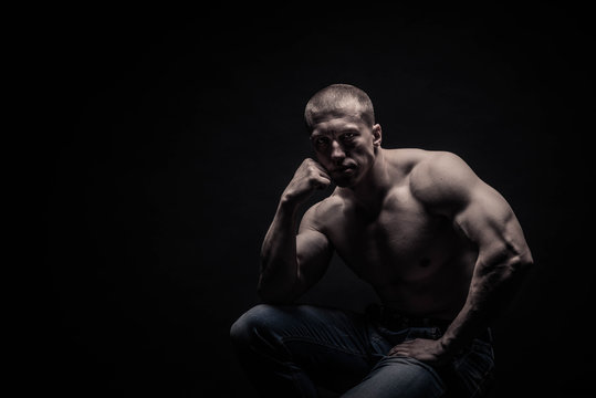 portrait of a seated male bodybuilder, on a black background isolated. monochrome. The concept of a photo of competing sports, health, fitness