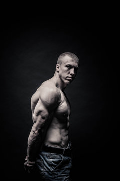 portrait of a male bodybuilder, straining muscles in sports poses, on a black background is isolated. monochrome. The concept of a photo of competing sports, health, fitness