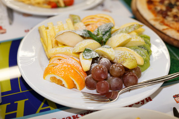 Mixed fresh fruits on white plate