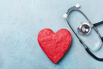 Red heart shape and medical stethoscope on blue background top view. Health care, medicare and...