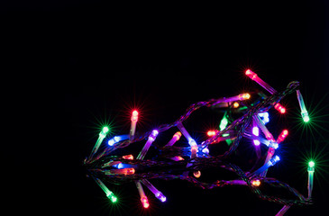 Christmas lights on reflective black background. Holiday shiny garland border. Xmas ligts concept