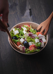 Greek salad and vegetables on the black wood table 