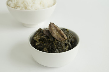 PRESERVED LETTUCE AND STEAMED  RICE
Chinese style preserved lettuce are served with steamed rice in a white bowl  on white background. 