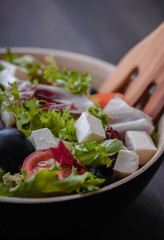 Greek salad and vegetables on the black wood table 
