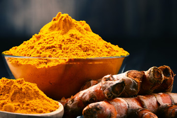 Composition with bowl of turmeric powder on wooden table