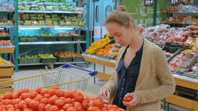 Woman buying red tomatoes at supermarket. Consumerism, sale, organic and health care concept