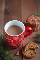Red Christmas mug of coffee and cookies on the wooden table