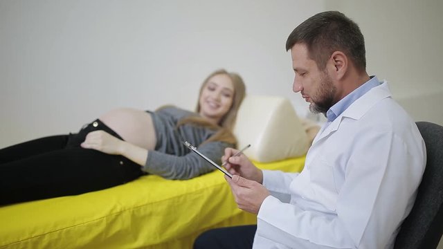 A doctor examines a pregnant woman and records the testimony in a medical record