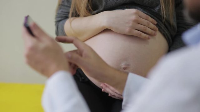 A doctor examines a pregnant woman and records the testimony in a medical record