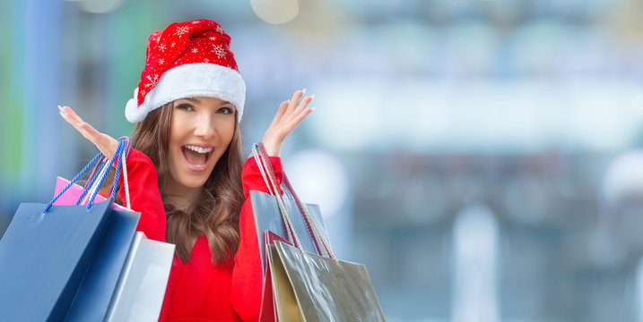 Christmas Shopping. Attractive Happy Girl With Credit Card And Shopping Bags In Santa Hat