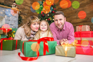 .Family of mother, father and little child daughter near Christmas tree with presents, decorations and New Year or Christmas
