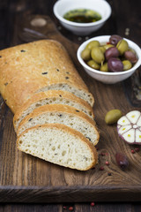 Italian ciabatta bread on board with herbs and olives