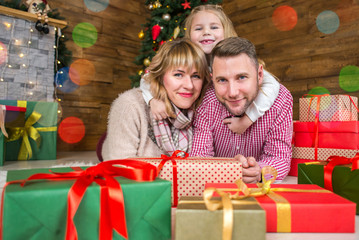 Fototapeta na wymiar .Family of mother, father and little child daughter near Christmas tree with presents, decorations and New Year or Christmas