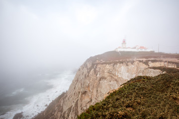 View on the Cape of the Rock with lighthouse during the foggy weather in Portugal