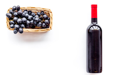 Bottle of red wine near bunch of grapes on white background top view copyspace