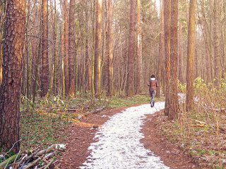 The girl runs along the snow trail in the autumn forest. Image on the topic of maintaining the body in good physical shape, strengthening health and immunity, a healthy lifestyle