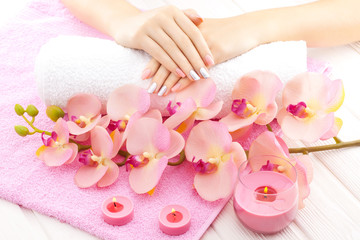 beautiful pink manicure with orchid, candle and towel on the white wooden table.