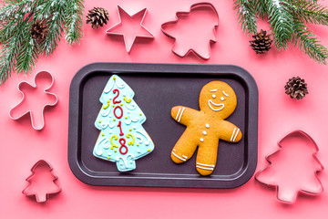Cookies for New Year. Gingerbread man and spruce with lettering 2018 near spruce branch on pink background top view