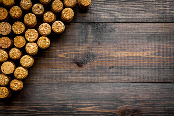 Corks of wine bottles pattern on dark wooden background top view copyspace