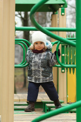 Two year old girl surmounting obstacle course on the winter playground