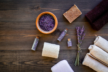 Floral foot spa with lavender. Spa salt, sponge, soap, towel on dark wooden background top view copyspace