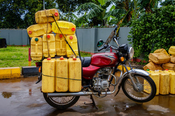 A typical boda boda, motorbike, in Uganda transporting many water canisters at once. The motorbike is parking at a gas station near Mbale.