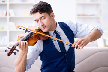 Young musician man practicing playing violin at home
