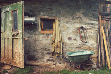 rustic farmer house, old country wall with wooden door and wheelbarrow