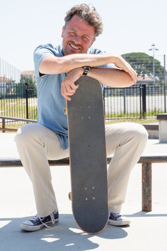 Trendy urban guy sitting on rail in skateboard park