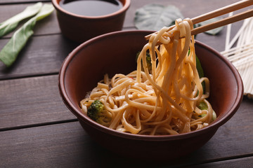 Bowl of rice noodles with soy souce on wood